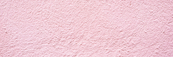 Fototapeta premium Pink textured wall surface with rough appearance showing colors and patterns in natural light during the day