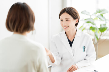 白衣を着て笑顔で説明する女性医師・カウンセリング風景