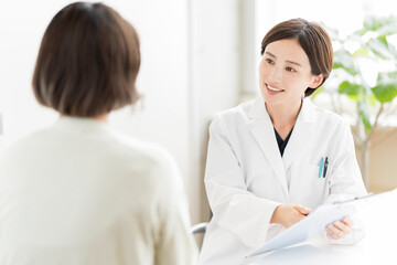 Fototapeta premium 患者を診察する白衣姿の日本人女性医師