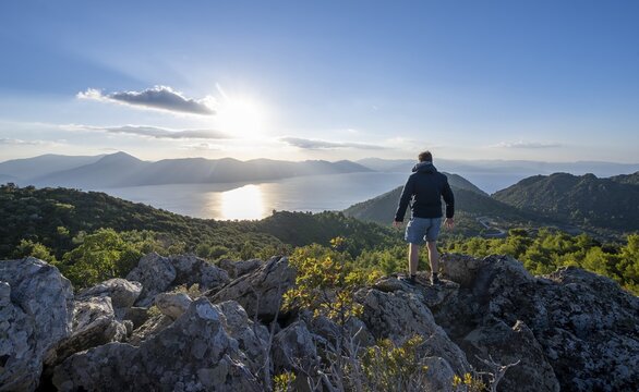 Hiker looking over volcanic peninsula Methana, view over sea and landscape with mountains and extinct volcanoes, Saronic Gulf, Peloponnese, Greece