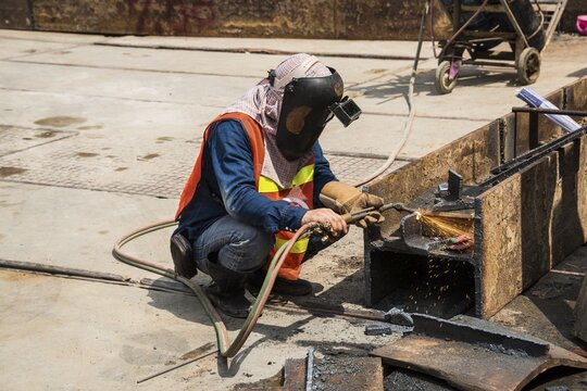 Worker welding steel beam on construction site, Bangkok, Thailand