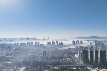 Aerial View of Modern Cityscape with High-Rise Buildings Emerging from Morning Fog © Dong