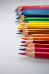 Fototapeta premium A Neatly Arranged Row of Colorful Pencils Displaying a Spectrum of Colors from Red to Purple on a White Background