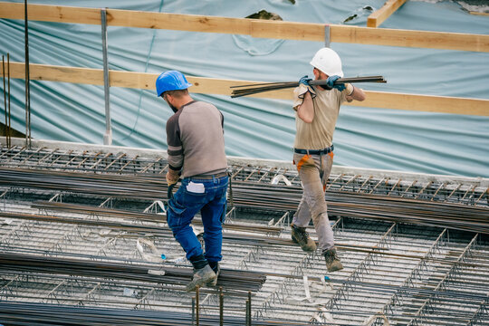Bauarbeiter tr&auml;gt Eisenstangen auf Baustelle