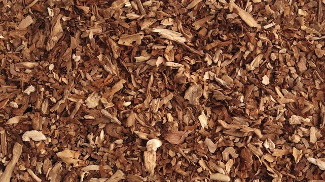 Dried tobacco flakes spread in top-down view forming layered texture with natural variation and soft shadows