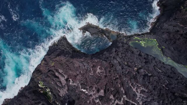 Aerial 4K drone footage of S&atilde;o Jorge Island, Azores, revealing lush volcanic cliffs, traditional village with red-roofed houses, terraced fields and rugged Atlantic coastline, Portugal.