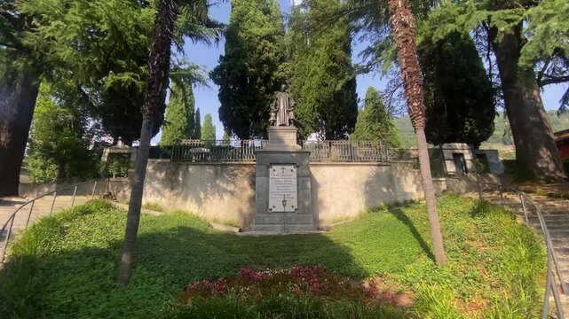 Commemorative statue of Monsignor Luigi Vitali entrance of the municipal cemetery Bellano, Italy