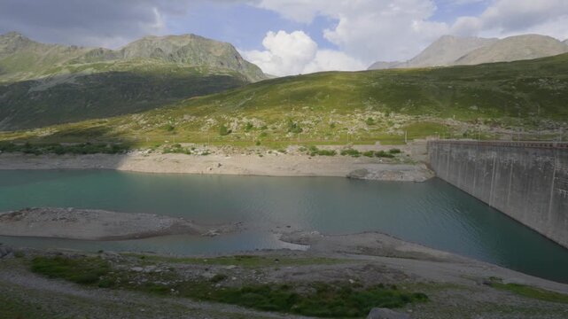 Concrete dam holding back a reservoir lake in a mountainous landscape Montespluga Dam in Italy