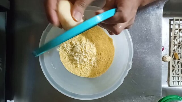 An unrecognizable person's hands are grating cheese onto a cornmeal mixture to make delicious arepas in a kitchen in Bosa, Bogota, Colombia. Concept of raw food
