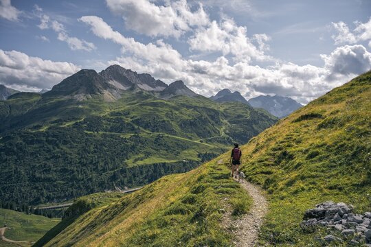 Female Hiker with Dog on Mountain Path Facing Karhorn and Warther Horn in the Arlberg Region, Austria