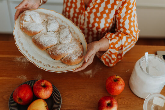 Happy senior woman with homemade easter braided bread with raisins. Close-up.