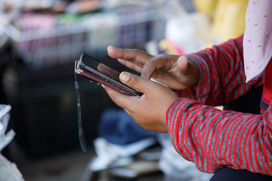 Female vendor's hands using smartphone, daily smartphone activity, modern urban routine, close up.