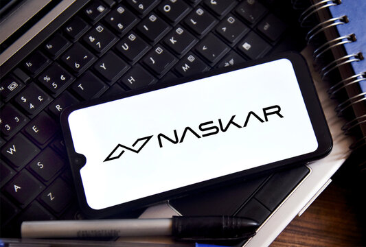 The fintech company Naskar's logo is displayed on a smartphone screen against an office background with a laptop and pens. Naskar fintech disappears with almost R$ 1 billion from Brazilian clients.