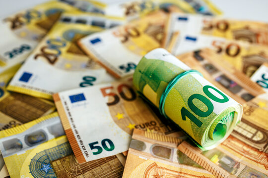 Euro currency background with bundled 100 euro notes placed over scattered banknotes. Concept banking and savings.
