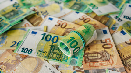 Obraz premium Macro close-up of rubber-banded 100 euro bills placed over mixed denomination euro banknotes. Concept wealth and financial stability. 