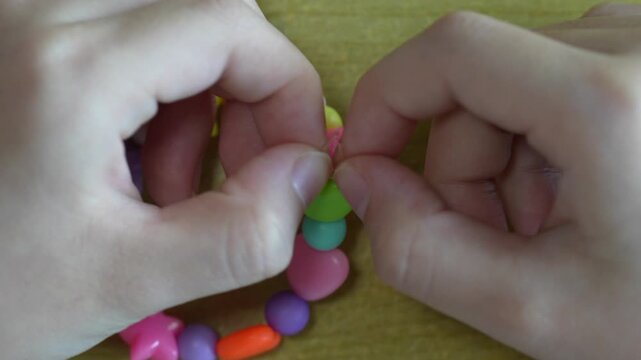 The last step of the bead bracelet feels small but important, as the child ties the string carefully and practices patience through playful craft work.