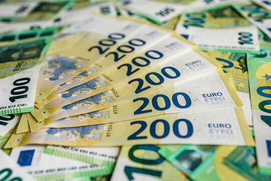 Euro banknotes scattered on flat surface with 100 and 200 euro notes included. Concept economy and cash flow.
