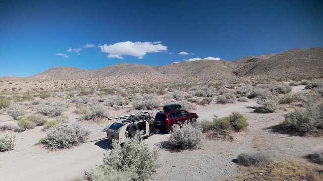 Aerial views show an SUV and teardrop camper trailer traveling through Prune Canyon in Anza Borego Desert State Park in California.