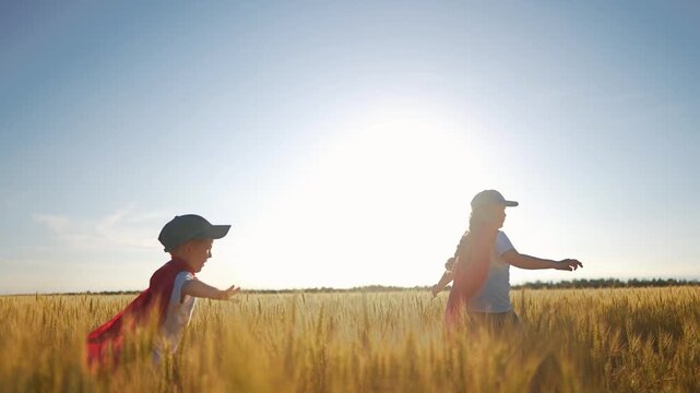 A group of kids playing a video game of superheroe together. Child hero fun concept. Superhero running through the wheat with children. A group of kids playing a game of sunset running together.