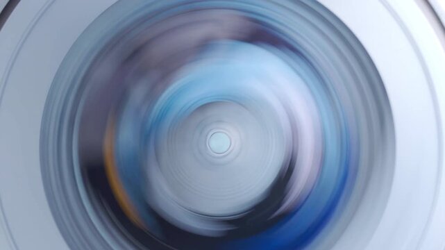 Top view of colorful clothes spinning inside a top-loading washing machine drum during wash cycle.