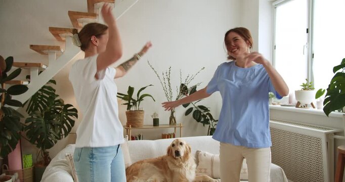Joyful female couple dancing together in their living room