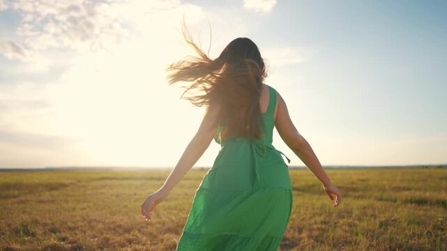 A girl runs free through nature. Wheat portrait lifestyle concept. A girl in a green dress silhouette runs through the park at sunset. Young girl running in nature at sunset lifestyle in the park.
