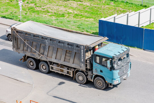 Shacman X3000 dump truck driving on a paved road, above front side view