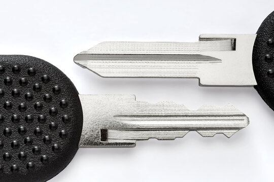 Technical macro of an automotive key blade with plastic head, shown beside its uncut blank. The image highlights the complex milled channels and coded track used in vehicle locking systems.
