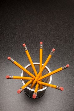 Yellow no.2 pencils in cup on desk in business office or school, view from above