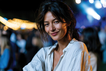 Naklejka premium Cheerful Woman Standing Confidently at Night Music Festival, Warm Smile and Joyful Expression, Colorful Stage Lights in Background, Social Connection and Vibrant Live Event Atmosphere Scene
