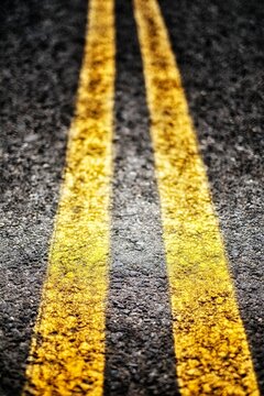 Extreme closeup of double yellow lines, parallel painted lines on the roadway leading away