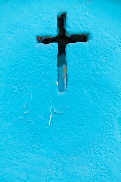 A weathered blue crypt wall with a cross-shaped cutout at a cemetery in Isla Mujeres. Symbolic, textured, and rich in cultural context.