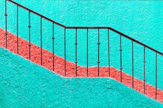 Bold turquoise wall with red stripe and iron railing in Cancun, Mexico. A vibrant, geometric composition perfect for modern design themes.