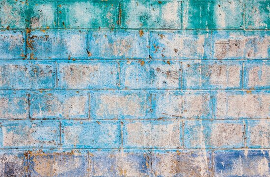 Aged and textured cinder block wall with fading blue, green, and purple paint, Mexico
