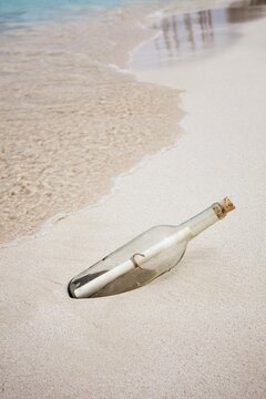 Glass bottle with rolled note washed up on beach, mystery, discovery, and lost messages.