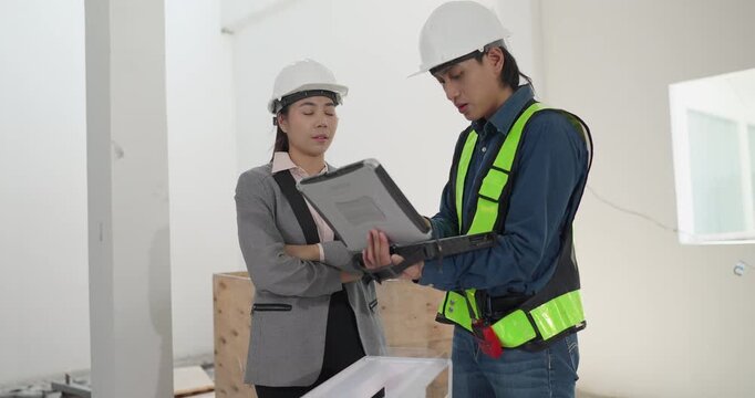 Male engineer and female architect review a building model, blueprints and a digital device at a residential construction site, planning design coordination and project development.
