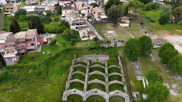 Aerial Drone View of the Historic Venetian Arsenal Ruins in Gouvia, Corfu Island, Greece. Ancient Stone Arches and Surrounding Coastal Village Landscape.