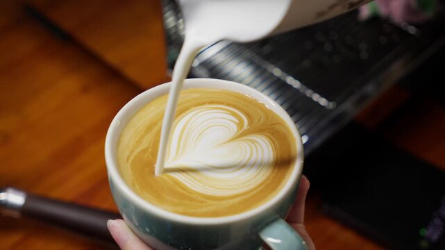 Professional barista crafts intricate latte art, the macro shot highlights the silky milk foam and dark espresso pour for a perfect coffee