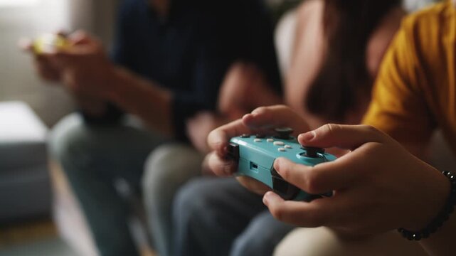 Son pressing gamepad buttons while competing with his father in a video game