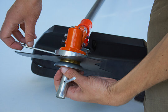 Close up of hands installing a metal blade on a brush cutter, A man installs a metal blade-disc on the gearbox of a brushcutter