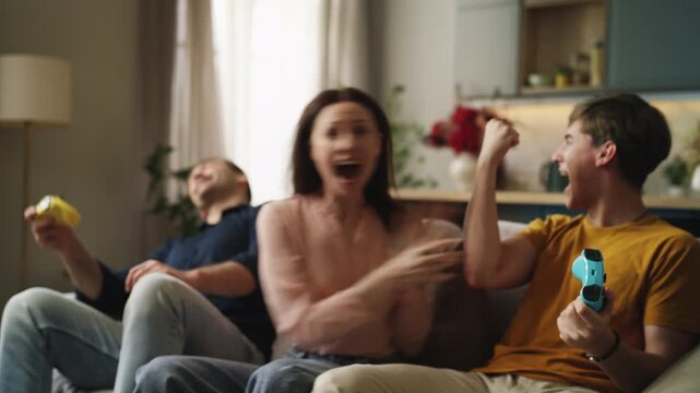Teenage boy competing with his father in a video game while mom cheers nearby