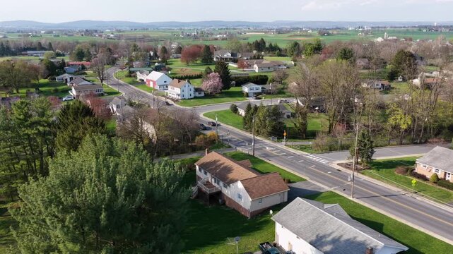 Main street in Akron,Pennsylvania with residential homes, light traffic and surrounding farmland during spring season showing rural small town living and open landscape in United States. Aerial Wide.