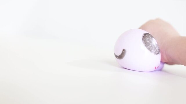 Child hand squeezing purple smiling dumpling squishy