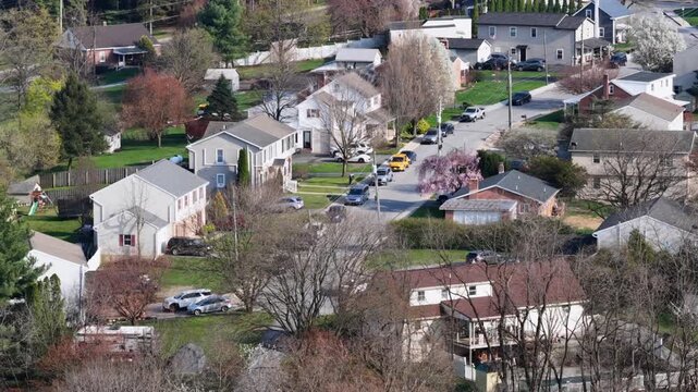 Quiet suburban neighborhood in Akron, Pennsylvania with single family homes, parked cars and blooming spring trees. Peaceful residential community scene in United States. Aerial view.