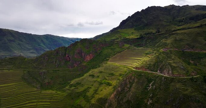 Terraced Inca landscape at Parque Arqueol&oacute;gico Pisac in the Sacred Valley, Peru, with mountain slopes, archaeological earthworks and a winding road, aerial view