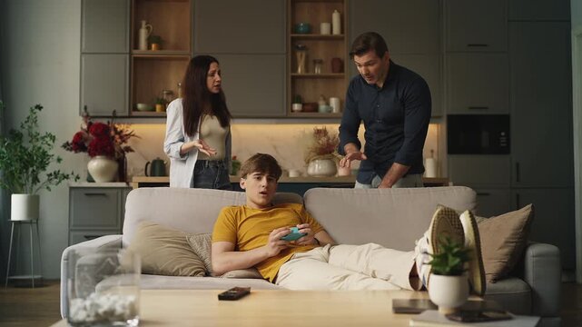 Parents scolding their teen son for playing video games, family conflict