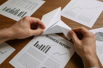 Naklejka premium Creative businessman folding a professional business report into a paper airplane to represent a startup launch and new project vision.