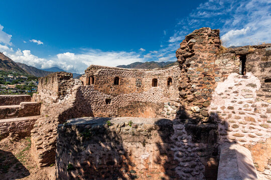 View of the ancient stone walls and arched windows of the Red Fort Muzaffarabad with distant mountains under a blue sky in Muzaffarabad, Azad Kashmir, Pakistan.