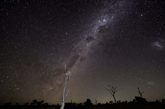 Wide shot of the Milky Way galaxy over a dark horizon and a dark sky.