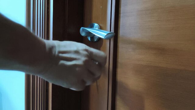 close-up footage of a hand turning a door lock with a key to unlock the door.